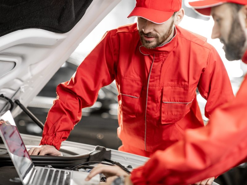 Auto mechanics doing diagnostics with laptop
